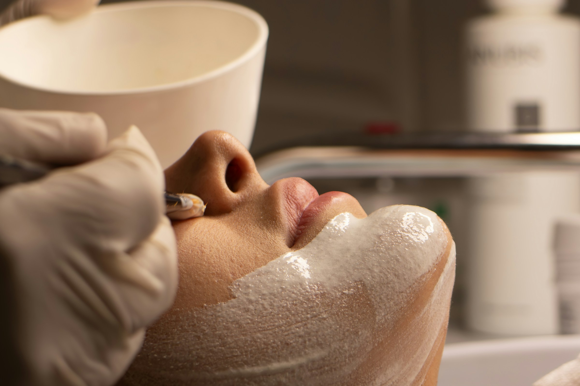 Esthetic professional applying a facial mask during a skin care service